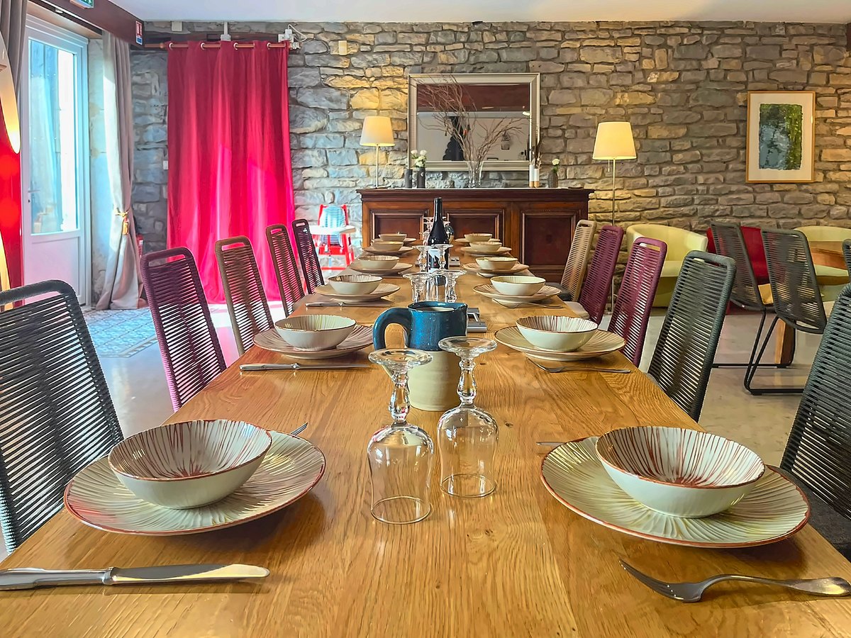 La grande table dressée sur toute sa longueur, devant le mur de pierre